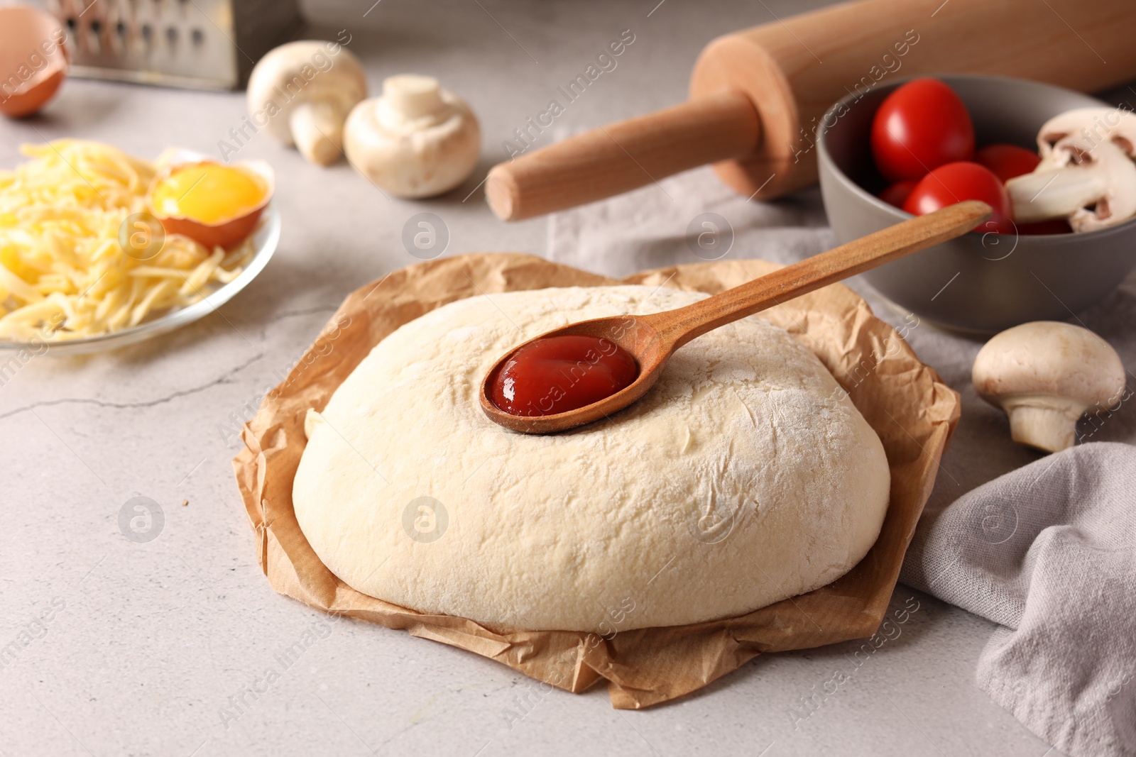 Photo of Pizza dough and products on gray textured table, closeup