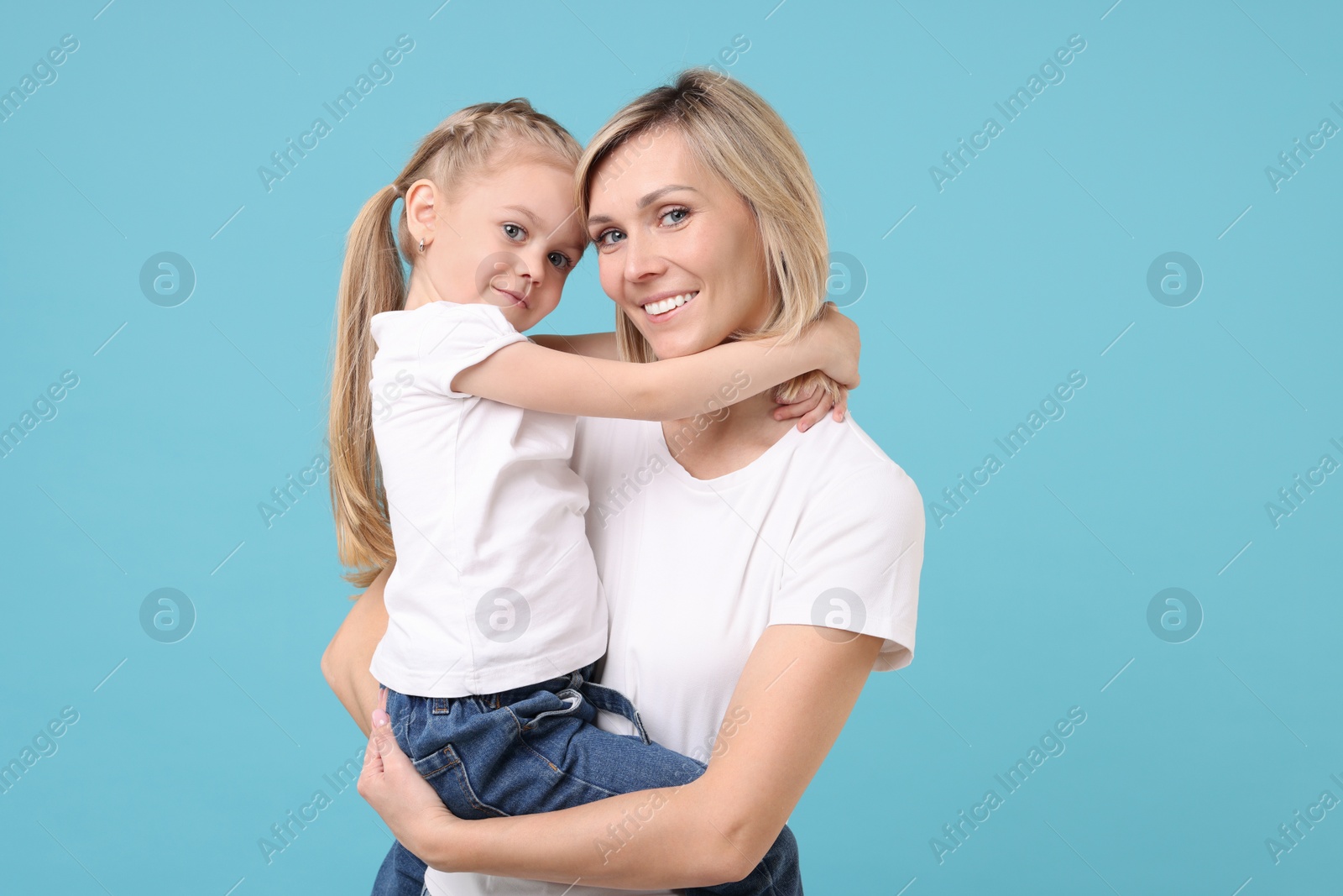 Photo of Family portrait of happy mother and daughter on light blue background