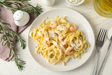 Photo of Delicious pasta with shrimps served on white wooden table, flat lay