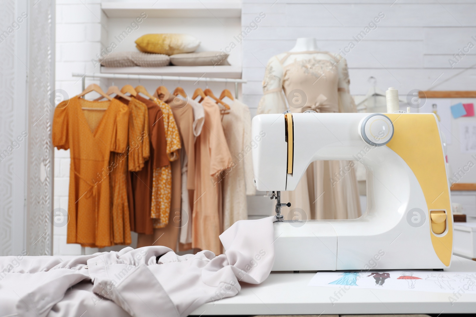 Photo of Modern sewing machine with fabric on table in dressmaking workshop