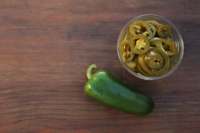 Fresh and pickled green jalapeno peppers on wooden table, flat lay. Space for text