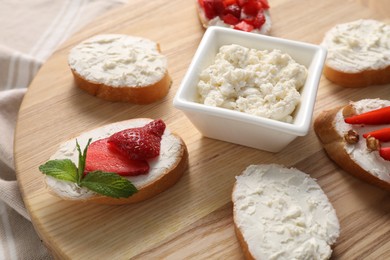 Photo of Different tasty ricotta bruschettas on wooden board, closeup