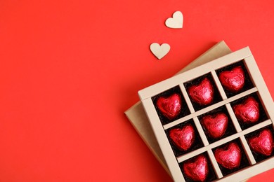 Photo of Tasty heart shaped chocolate candies on red background, flat lay with space for text. Happy Valentine's day