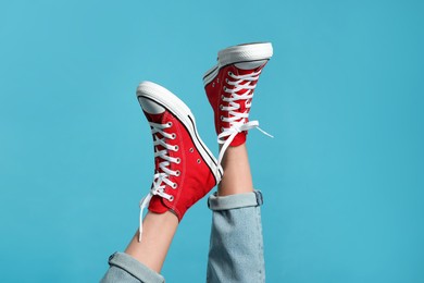 Photo of Woman in stylish gumshoes on light blue background, closeup