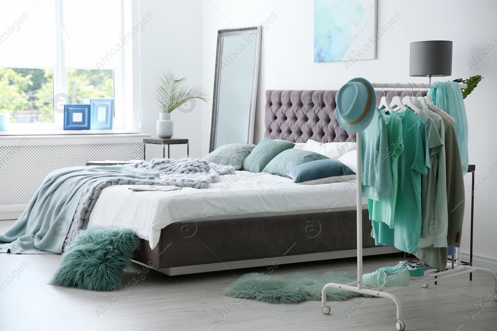 Photo of Stylish bedroom interior with clothes rack and mint decor elements