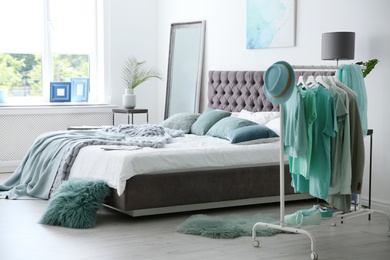 Stylish bedroom interior with clothes rack and mint decor elements