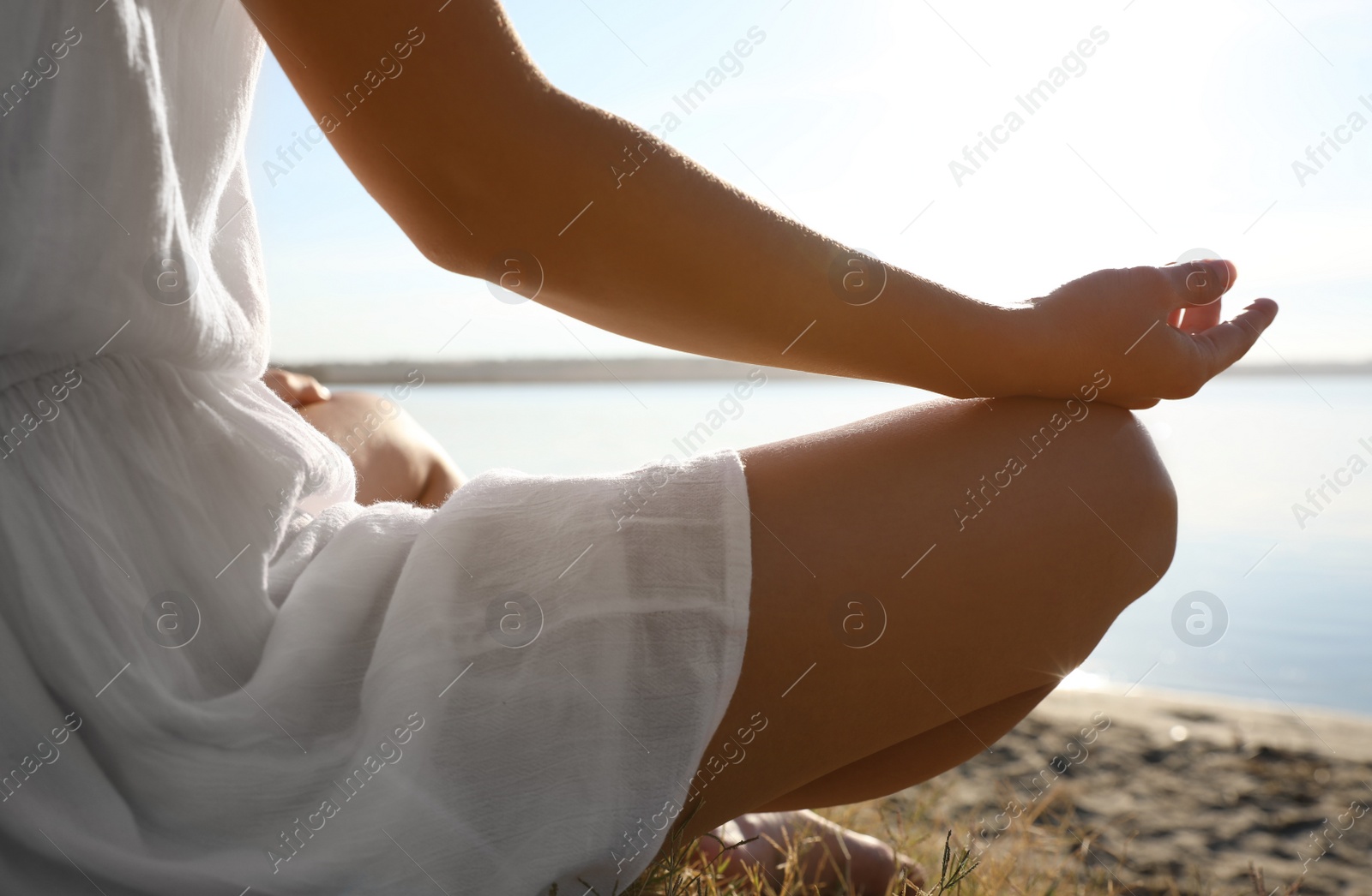 Photo of Young woman meditating near river at sunset, closeup. Nature healing power