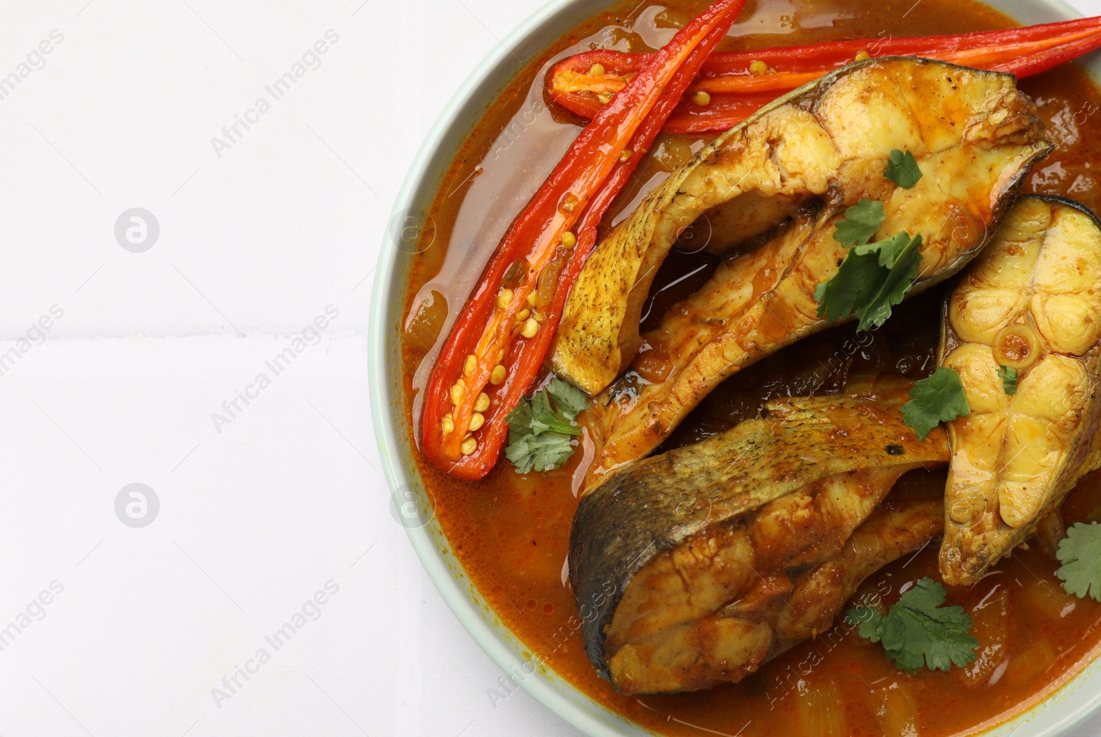 Photo of Tasty fish curry on white table, top view. Space for text. Indian cuisine