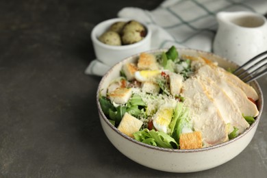 Photo of Delicious Caesar salad in bowl on grey table, space for text