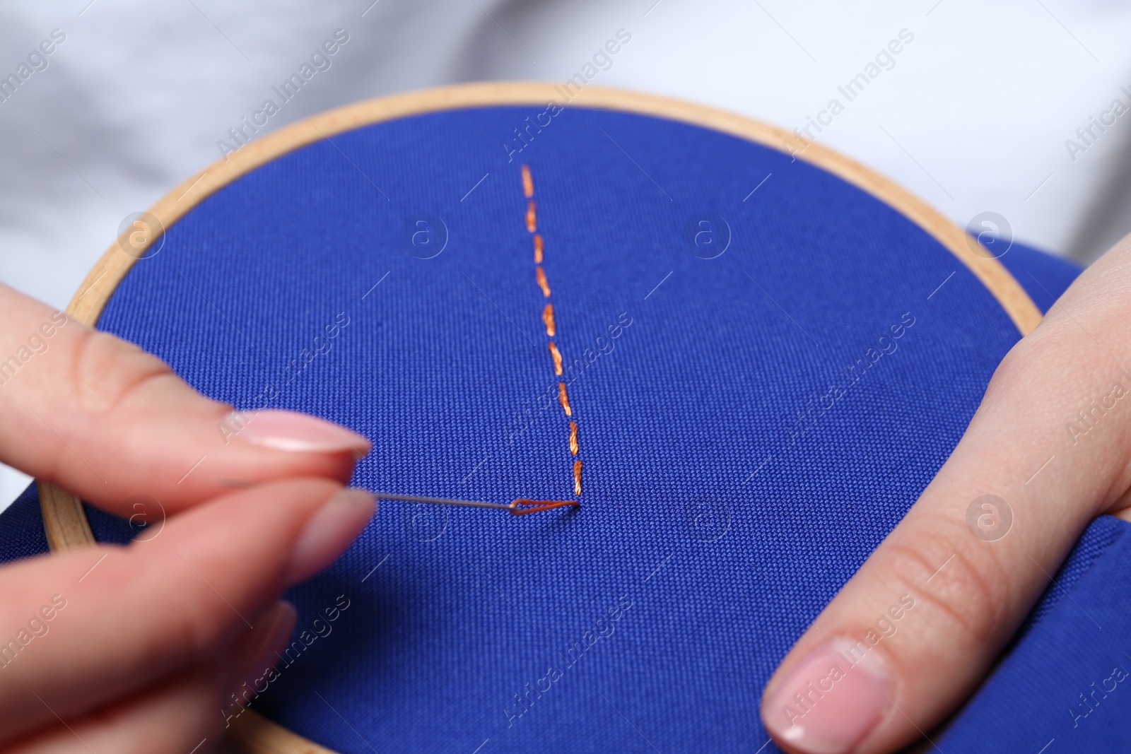 Photo of Woman with sewing needle and thread embroidering on cloth, closeup