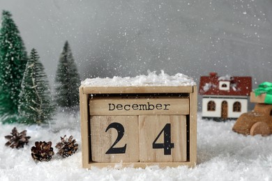 Photo of December 24 - Christmas Eve. Wooden block calendar and festive decor covered with snow