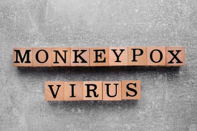 Photo of Words Monkeypox Virus made of wooden cubes with letters on light grey background, top view