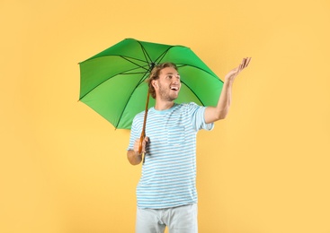 Photo of Man with green umbrella on color background