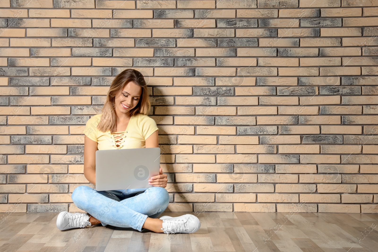 Photo of Portrait of beautiful woman with laptop near brick wall