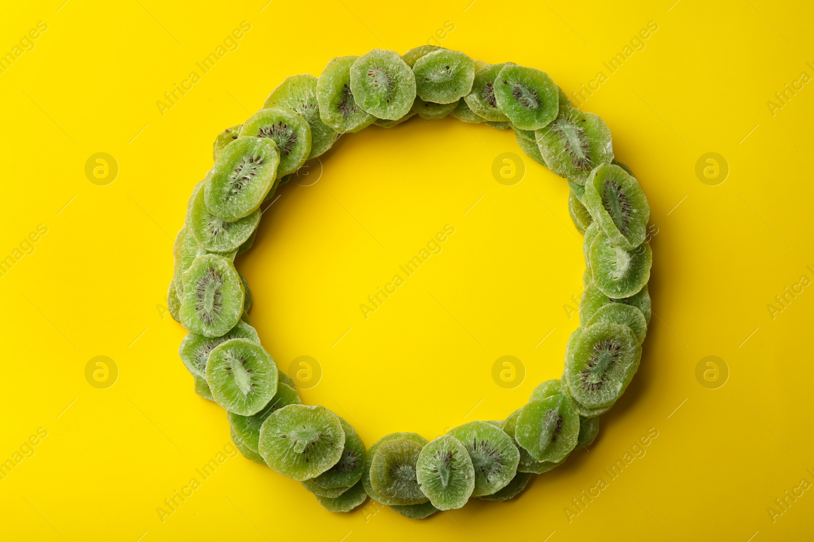 Photo of Frame made of kiwi on color background, top view with space for text. Dried fruit as healthy food