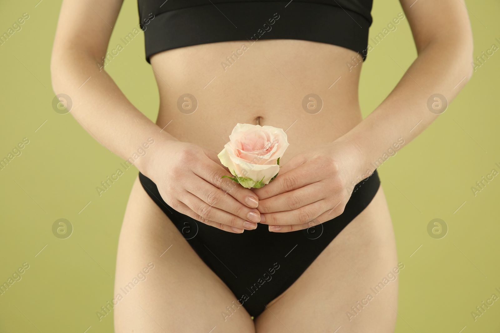 Photo of Gynecology. Woman in underwear with rose flower on green background, closeup