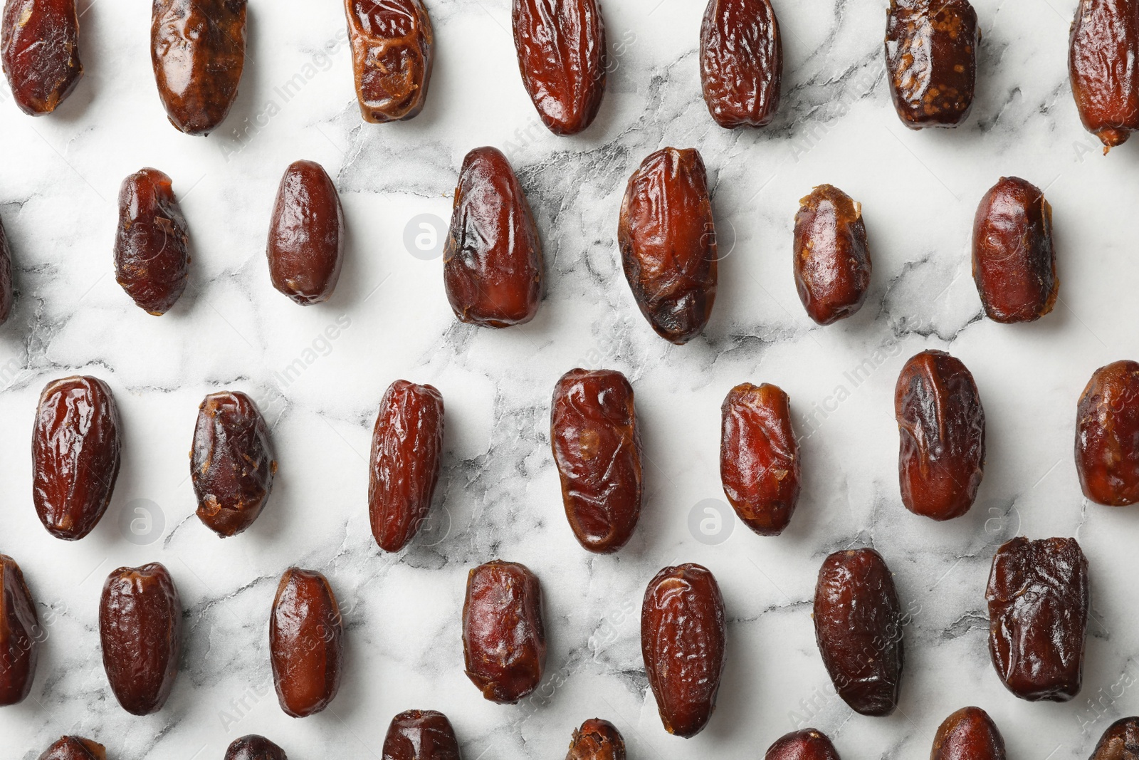 Photo of Flat lay composition with dates on marble background. Dried fruit as healthy snack