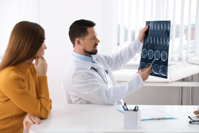 Photo of Orthopedist showing X-ray picture to patient at table in clinic