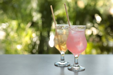 Photo of Delicious refreshing drinks on grey table outdoors. Space for text