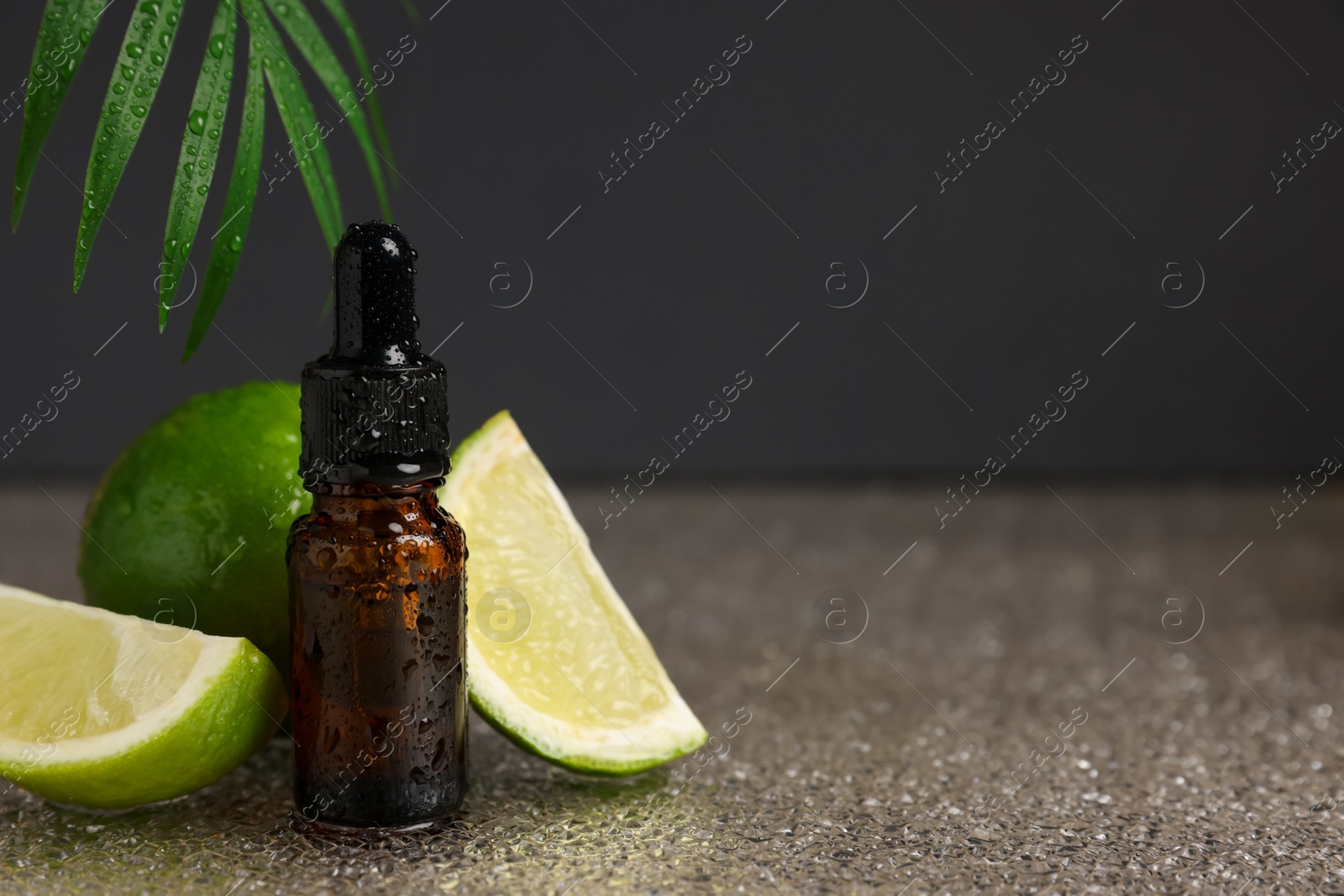 Photo of Bottle of organic cosmetic product and sliced lime on wet surface, space for text