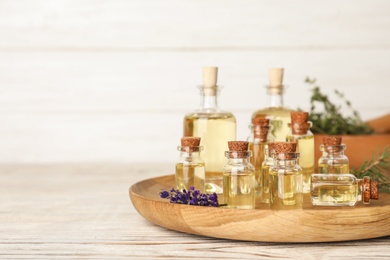 Different essential oils in glass bottles on table. Space for text