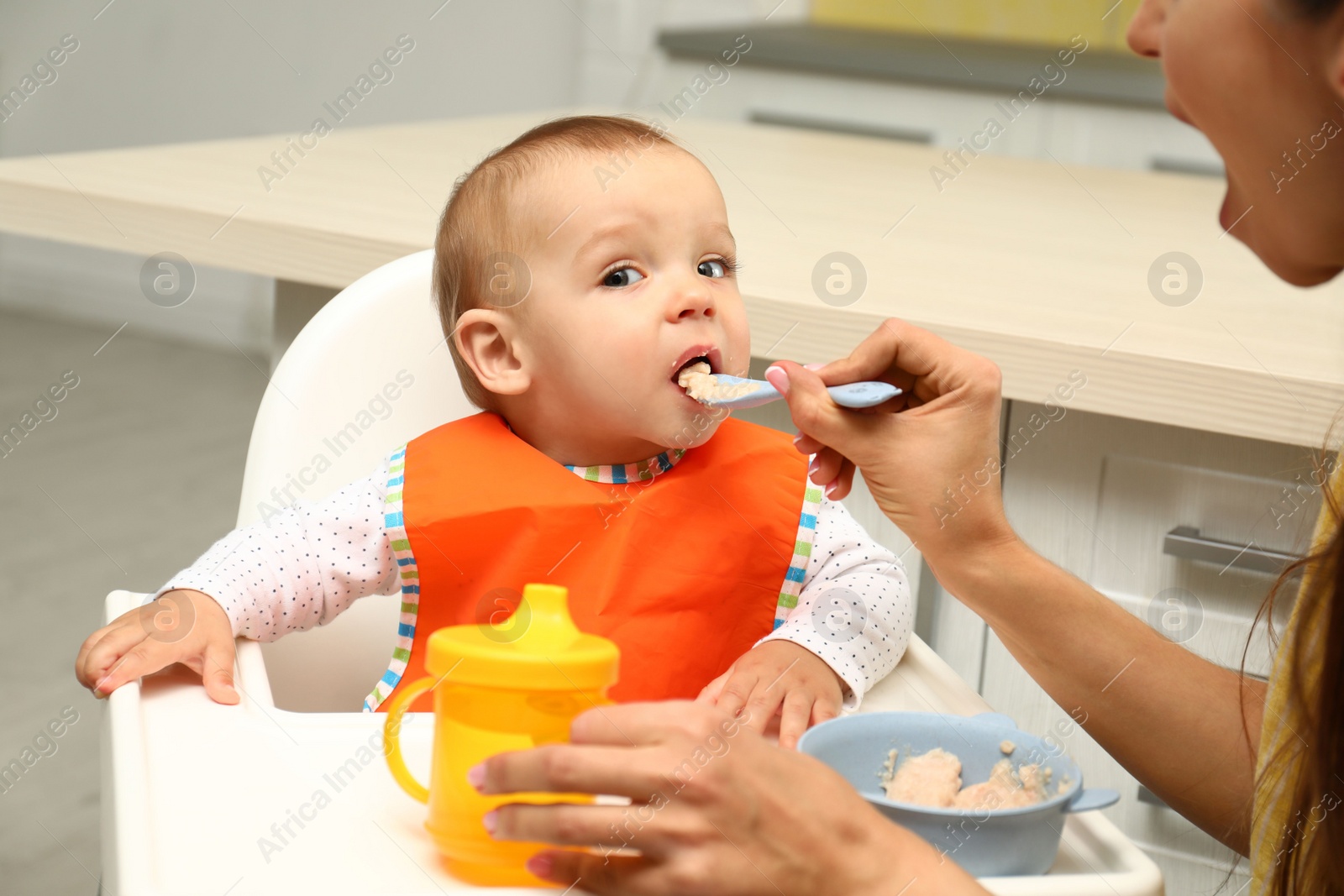 Photo of Young mother feeding her little baby at home