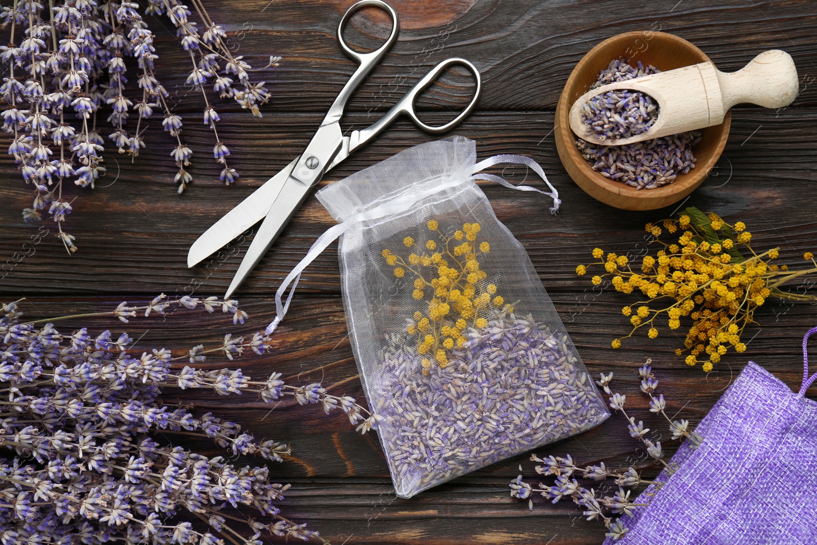 Photo of Scented sachet with mixed dried flowers and scissors on wooden table, flat lay