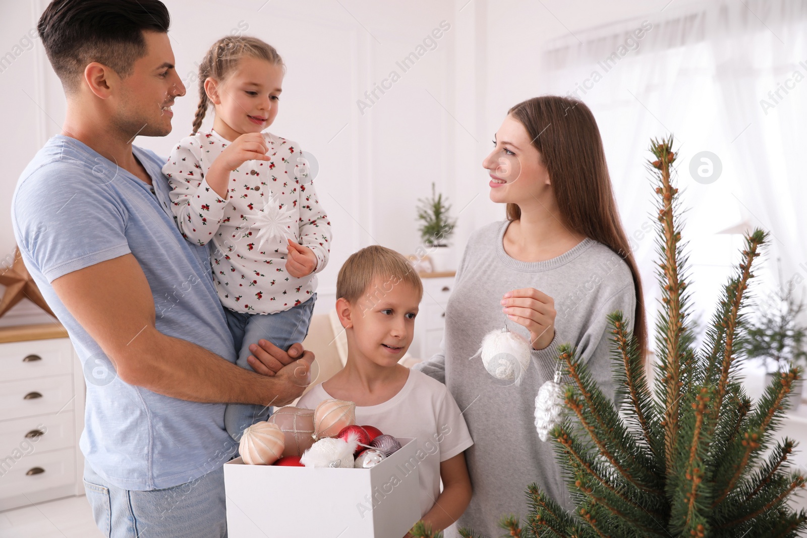 Photo of Happy family with cute children decorating Christmas tree together at home