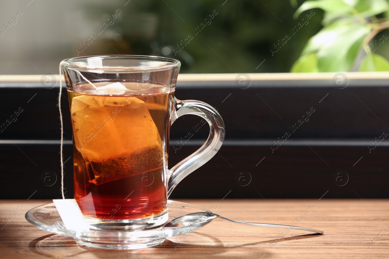 Photo of Glass cup of hot tea on wooden window sill. Space for text