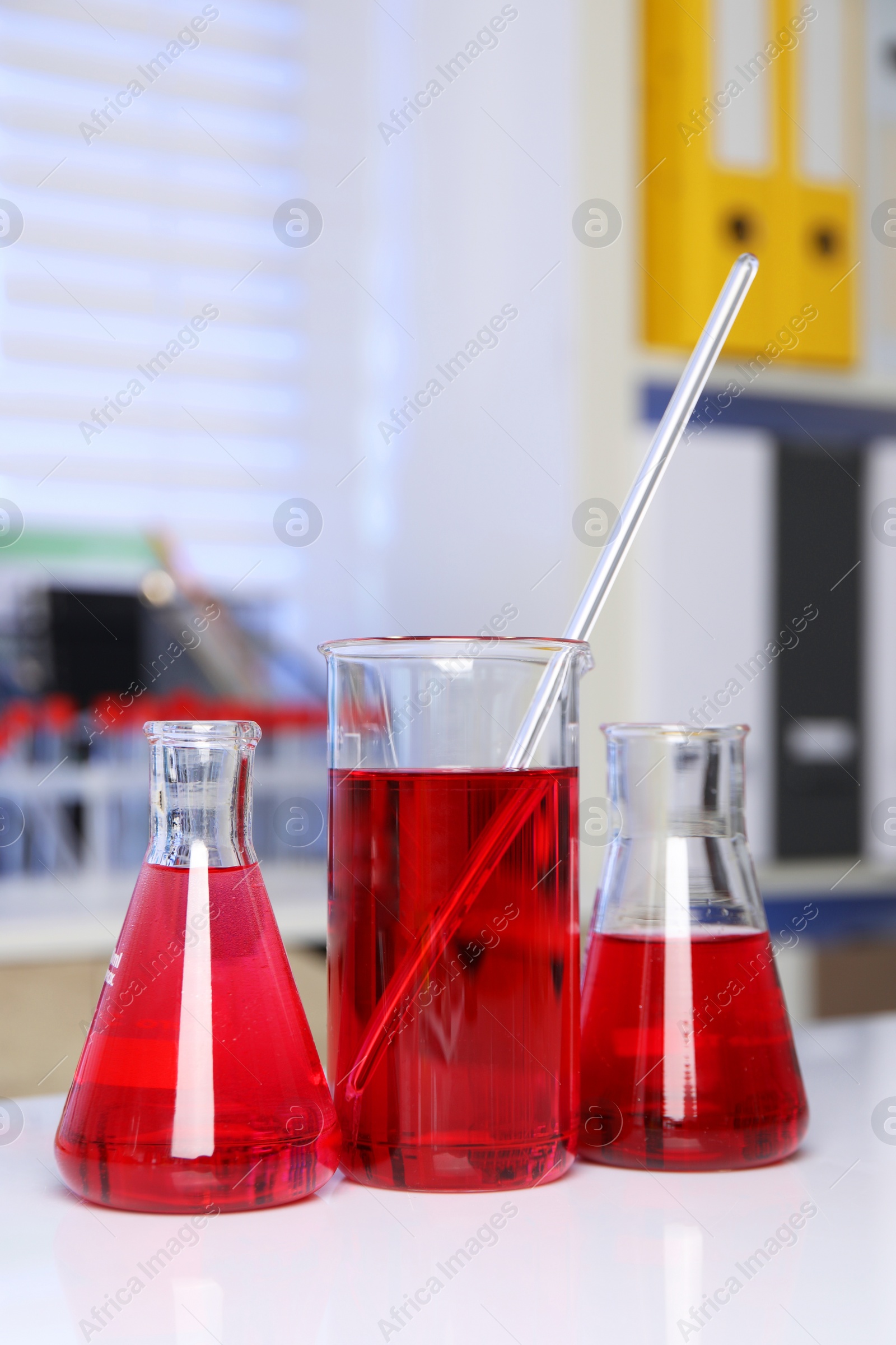 Photo of Laboratory analysis. Different glassware with red liquid on white table indoors