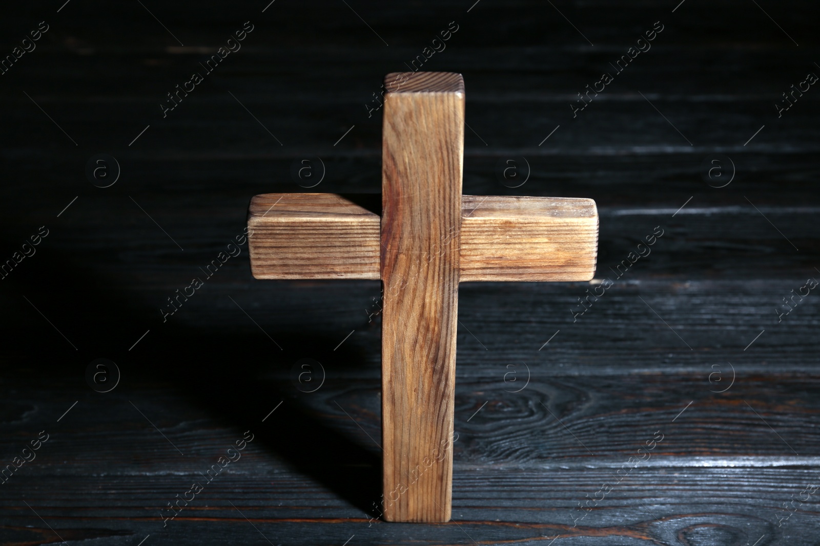 Photo of Christian cross on wooden table, above view. Religion concept