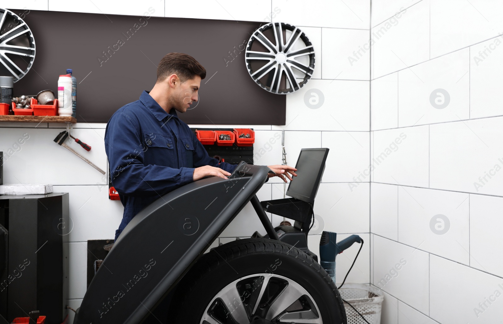 Photo of Man working with wheel balancing machine at tire service