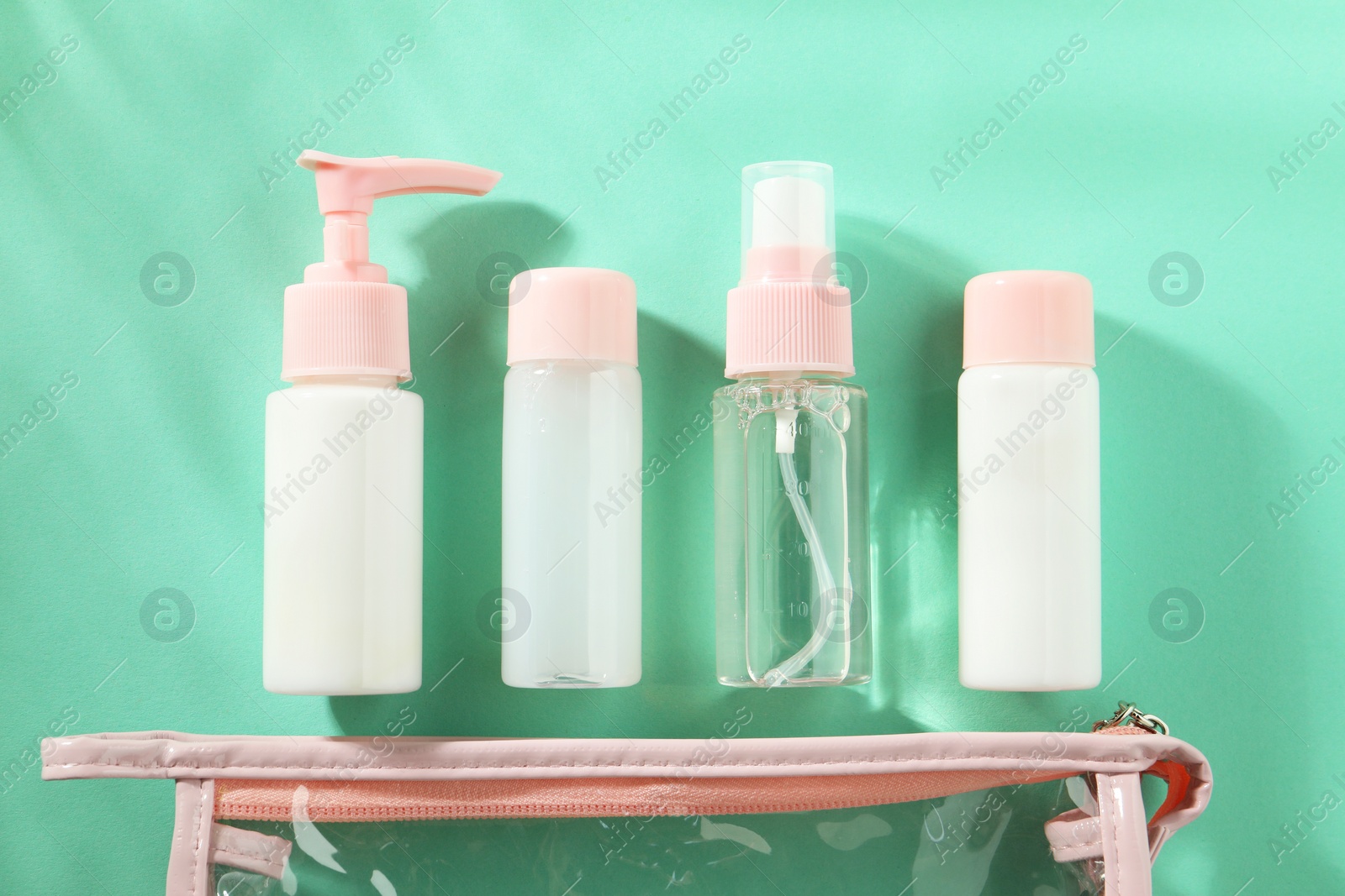 Photo of Cosmetic travel kit with plastic bag on turquoise background, top view