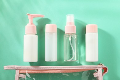 Photo of Cosmetic travel kit with plastic bag on turquoise background, top view