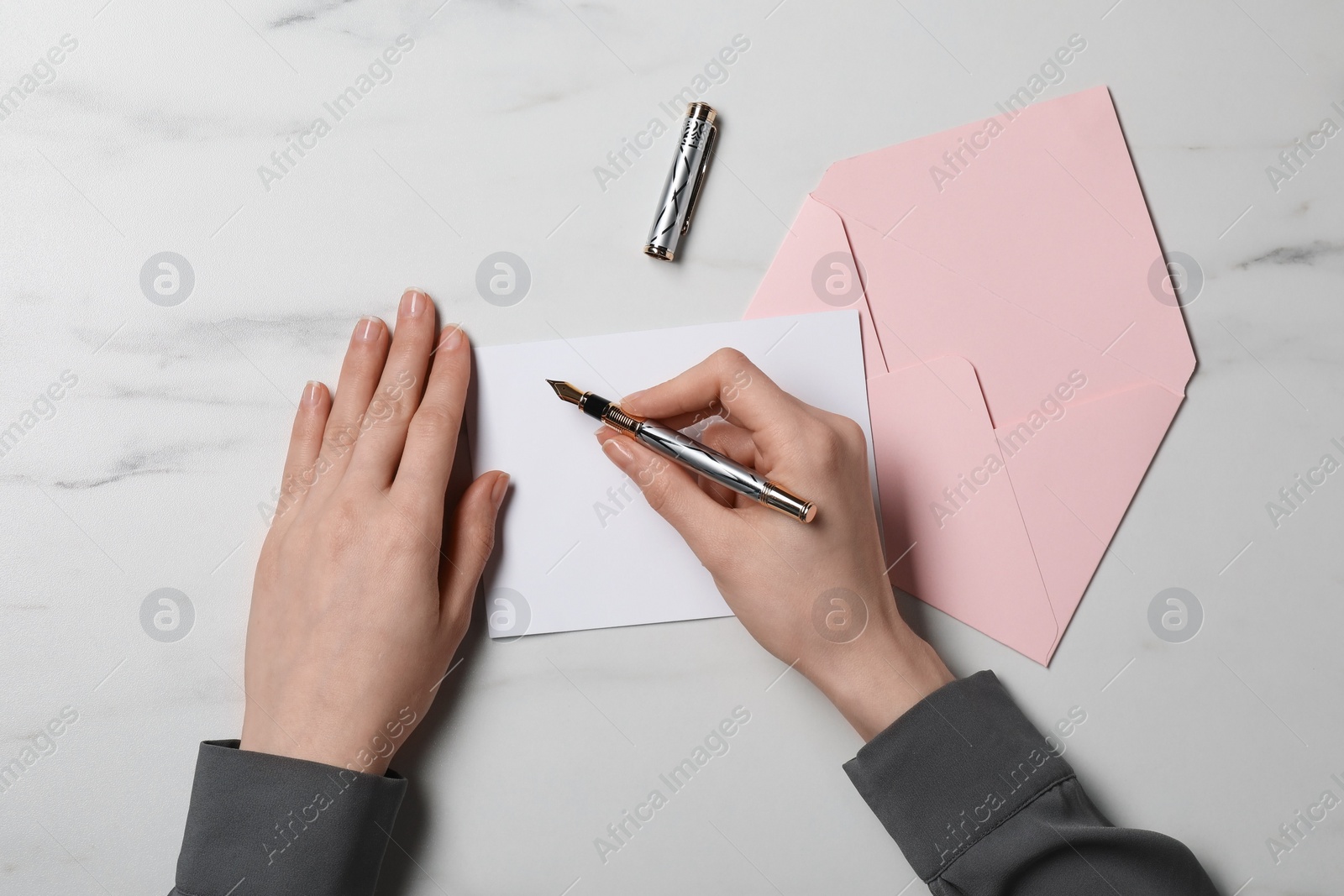 Photo of Woman writing letter at marble table, top view