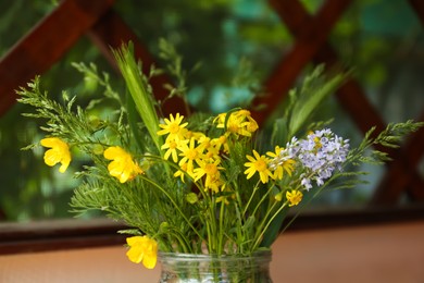 Photo of Bouquet of beautiful wildflowers in glass vase against blurred background, closeup