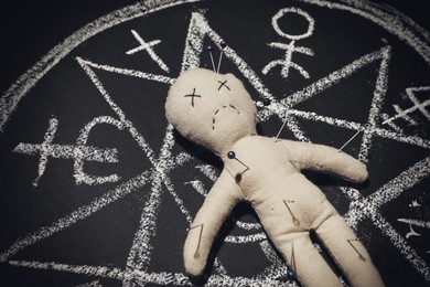 Photo of Voodoo doll in ritual circle drawn on black table, closeup