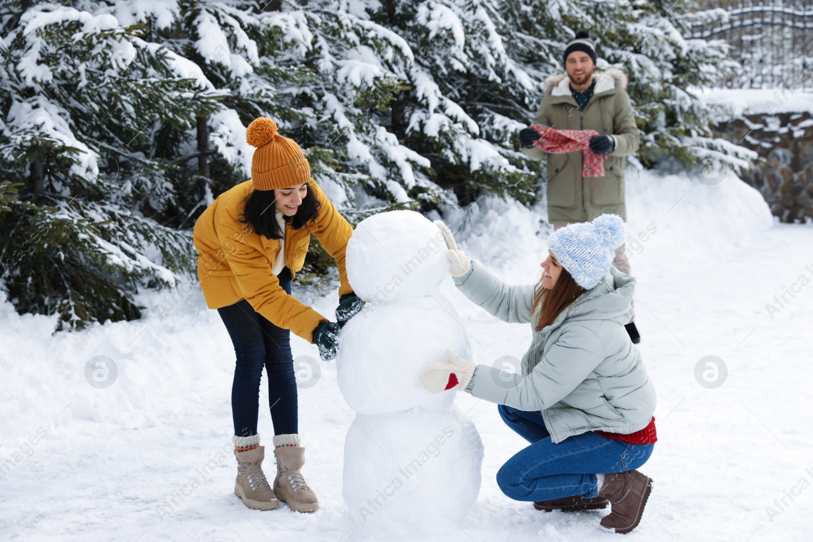 Photo of Happy people making snowman together outdoors. Winter vacation