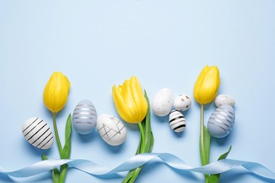 Flat lay composition with tulips and beautifully painted eggs on light blue background, space for text. Easter celebration