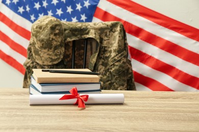 Photo of Diploma, books and soldier uniform near flag of United States. Military education