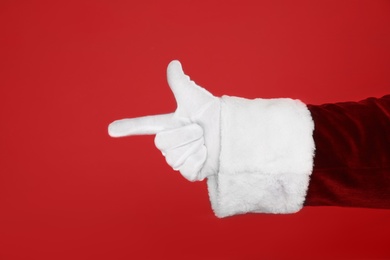 Photo of Santa Claus pointing at something on red background, closeup of hand