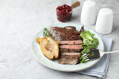 Photo of Delicious roasted beef meat, caramelized pear and greens served on light textured table. Space for text