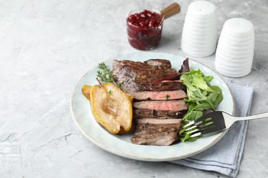 Delicious roasted beef meat, caramelized pear and greens served on light textured table. Space for text