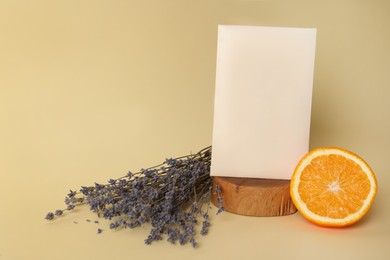 Photo of Scented sachet, dried lavender and half of orange on beige background