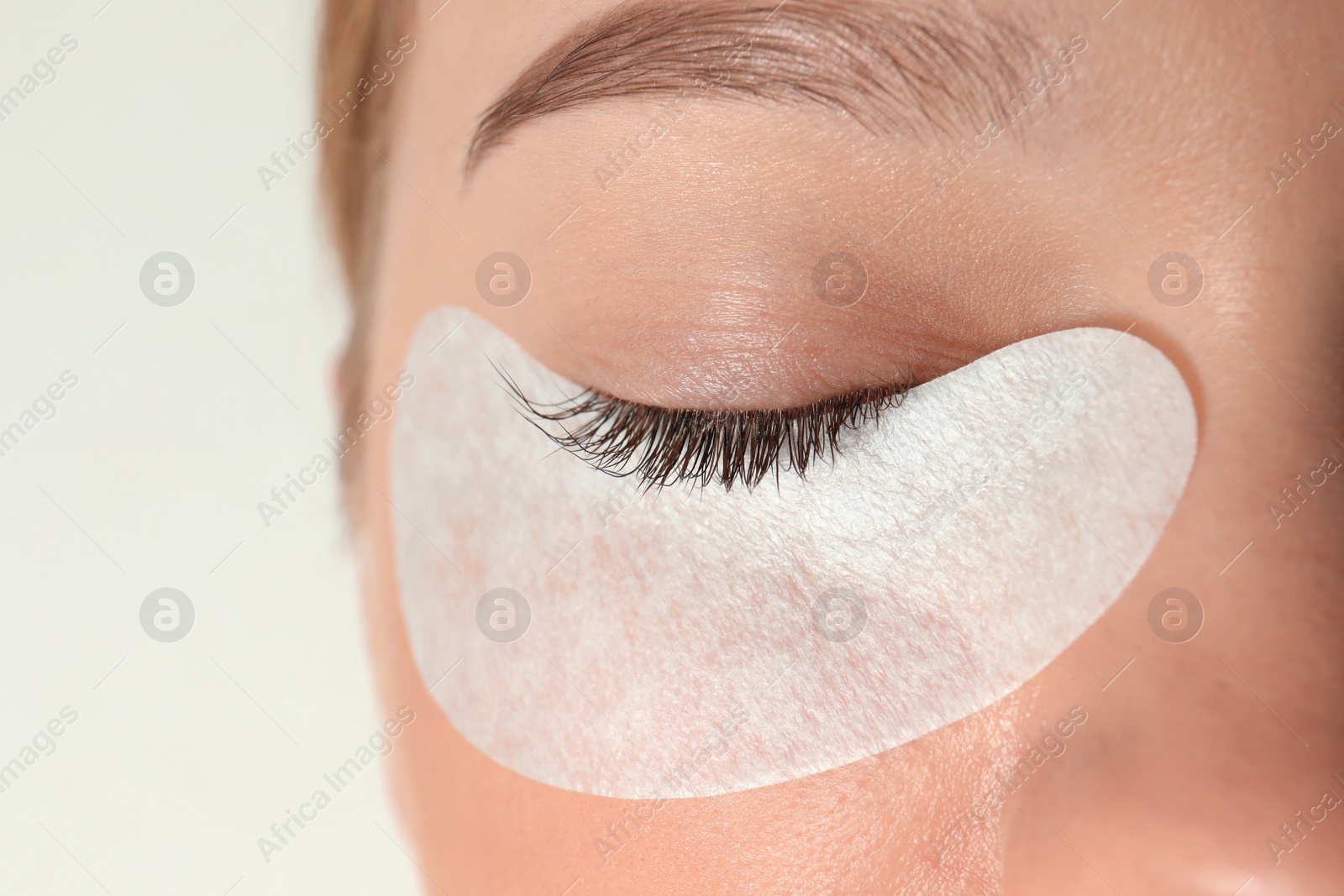 Photo of Young woman undergoing eyelash extension procedure, closeup