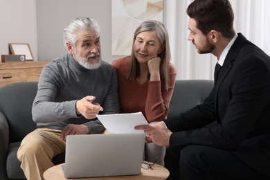 Insurance agent consulting elderly couple about pension plan in room