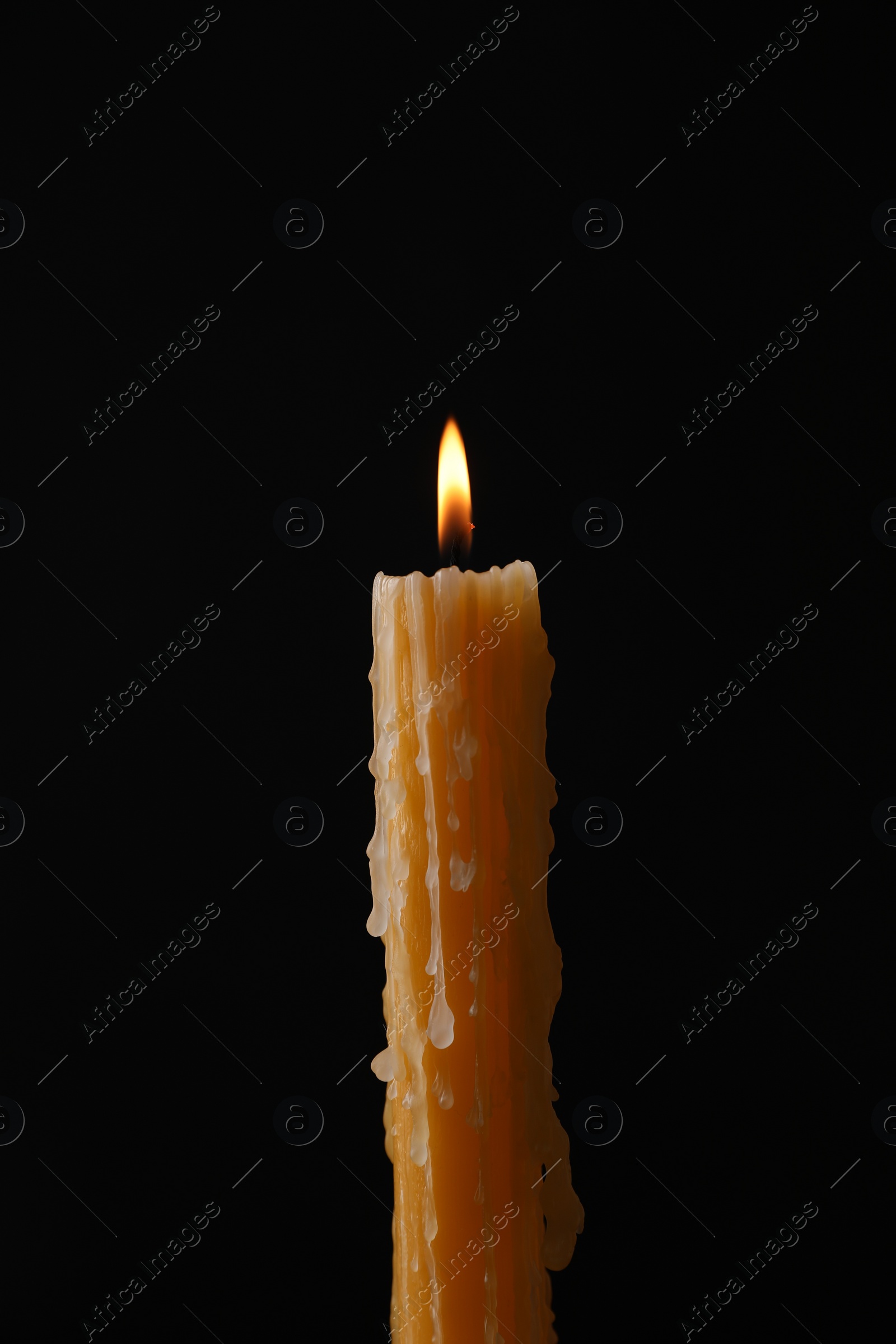 Photo of Burning church wax candle on black background