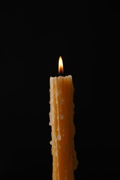 Photo of Burning church wax candle on black background