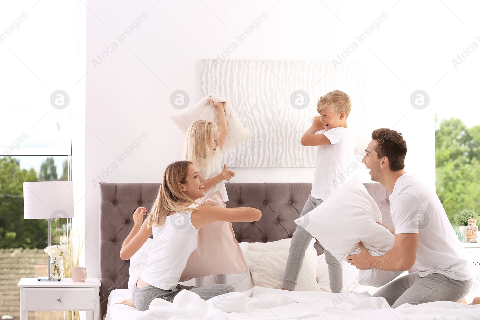 Photo of Happy family having pillow fight on bed at home