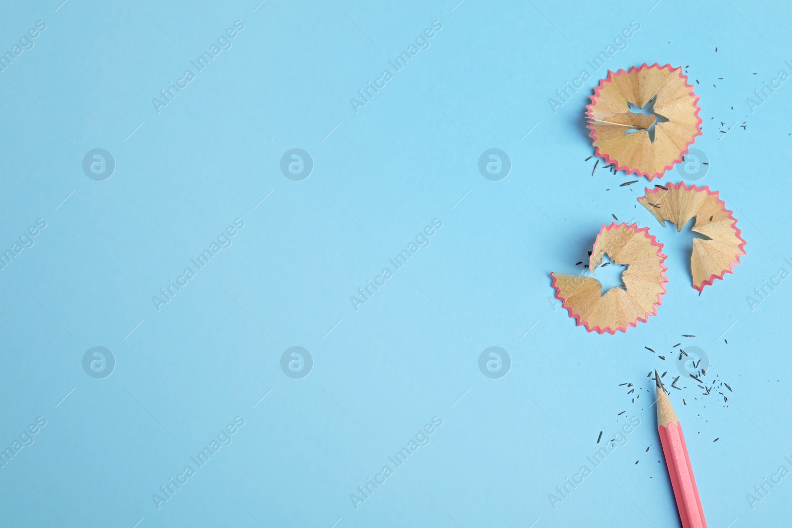Photo of Pencil and shavings on blue background, flat lay. Space for text